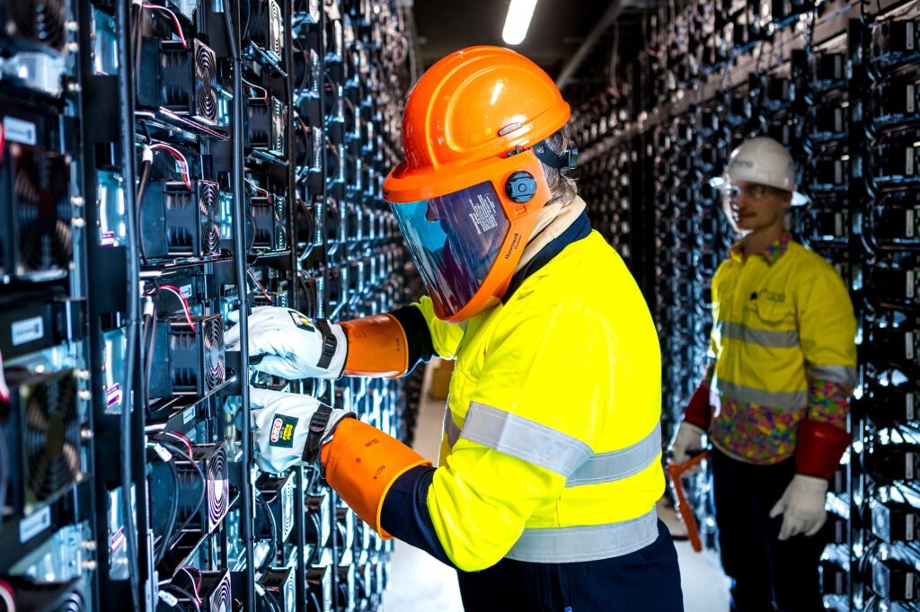 Engineers in high visibility workwear at the walls of battery terminals inside Wandoan South BESS project in Queensland. 