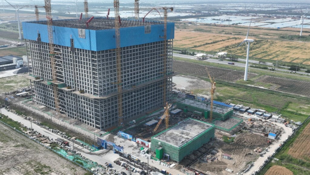 Energy Vault's gravity storage system, a large cubical building-like structure, circled by wind turbines at a site in Rudong, China. 