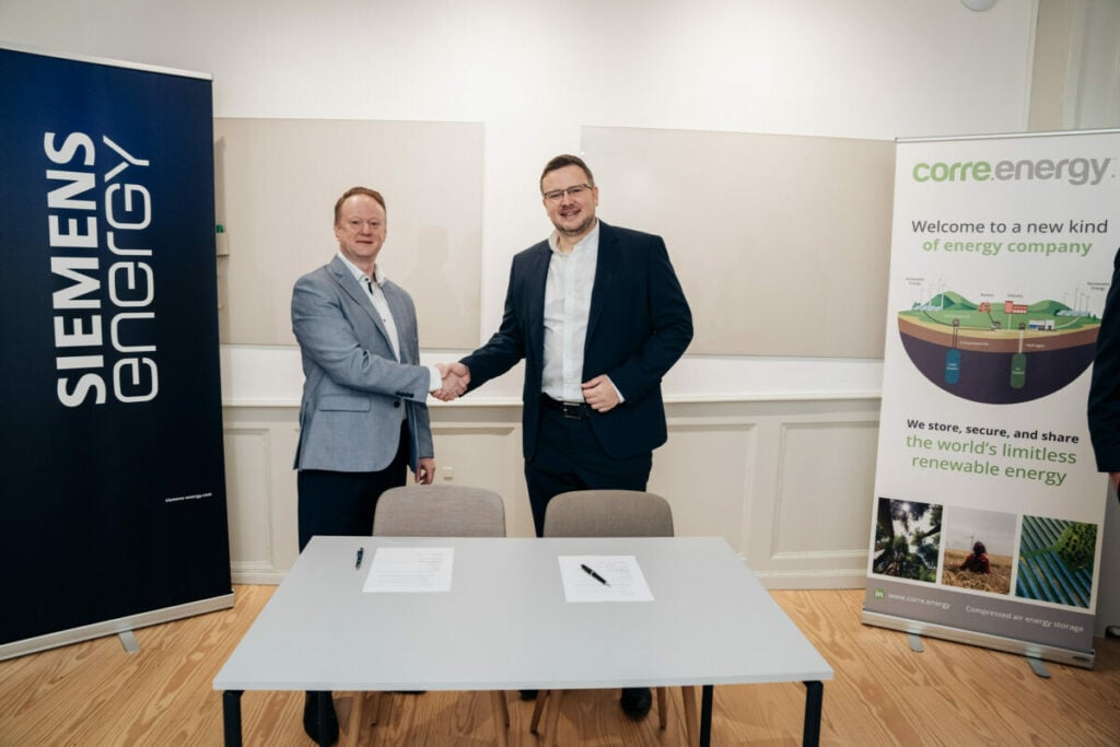 Representatives of Siemens Energy and Corre Energy shake hands on their collaboration agreement, flanked by banners for each of their companies. long-duration