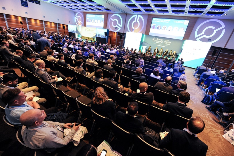 Overhead shot of a crowded auditorium with panellists onstage at the front, taken at this year's Energy Storage Summit EU. 
