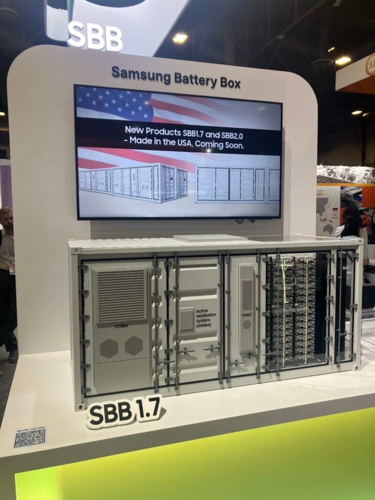 A mocked up scale model of the Samsung SDI SBB 1.7 BESS solution underneath a screen displaying US flag colours and announcing their domestic manufacturing status.