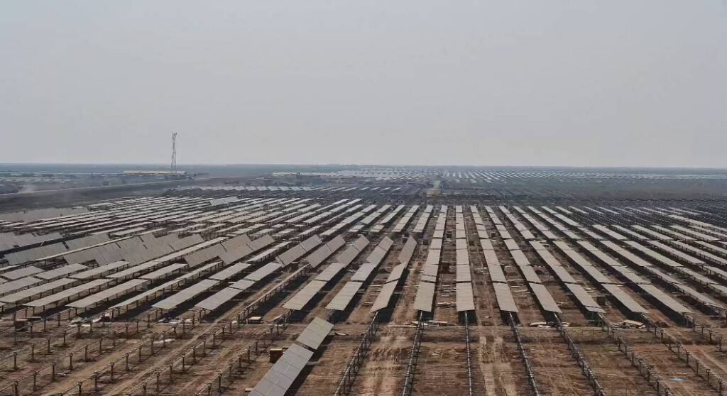 Solar photovoltaic arrays stretch into the distance under an overcast sky. 